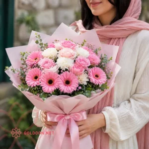 خرید دسته گل صورتی و سفید شامل گل‌های ژربرا، رز و میخک با بسته‌بندی و روبان صورتی از گلدون goldoon.net