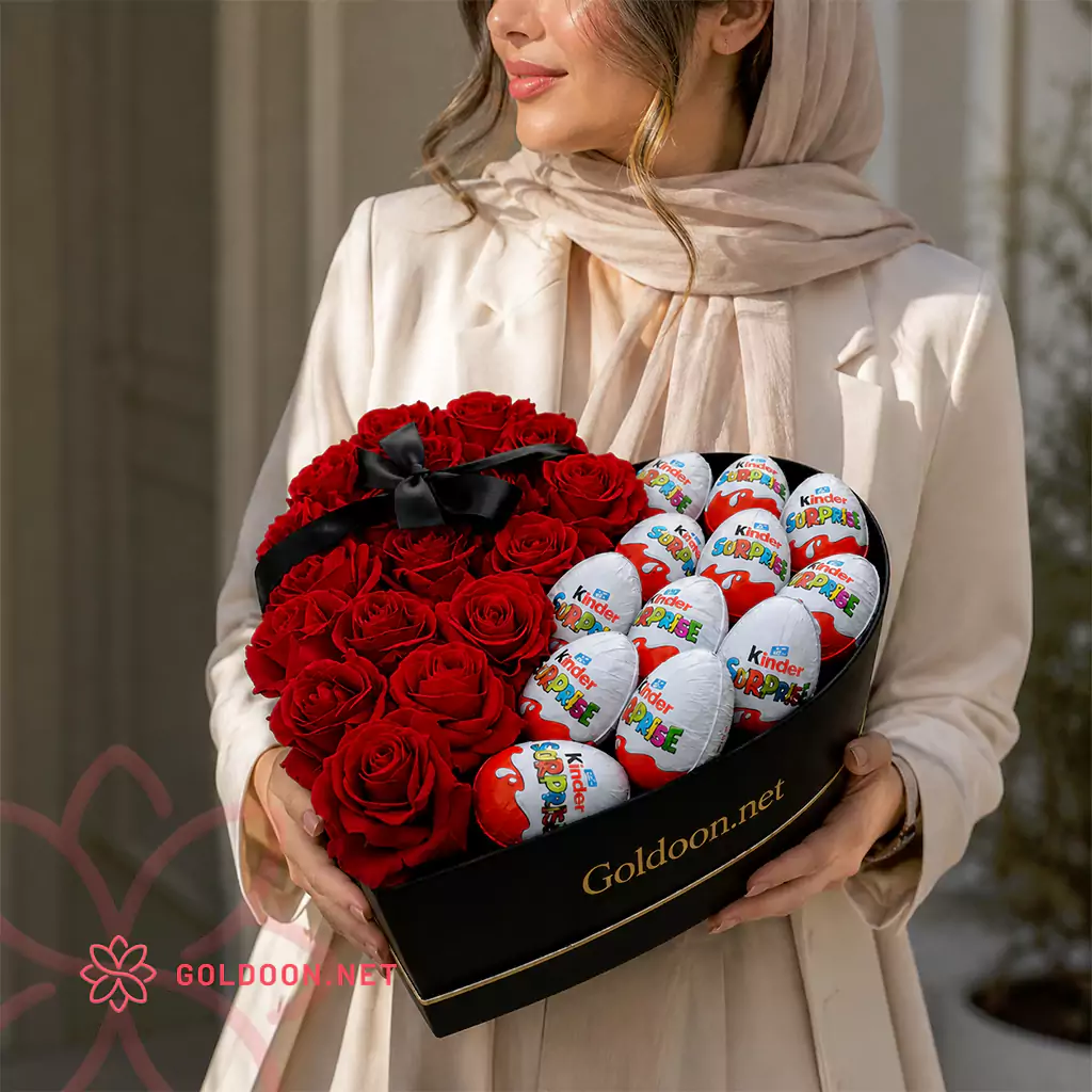 باکس گل و شکلات کد 025 از گلدون؛ ترکیبی از 20 شاخه رز هلندی قرمز و 12 عدد شکلات کیندر در باکس قلبی لوکس؛ با ابعاد تقریبی 35 در 35 در دستان مدل خانم