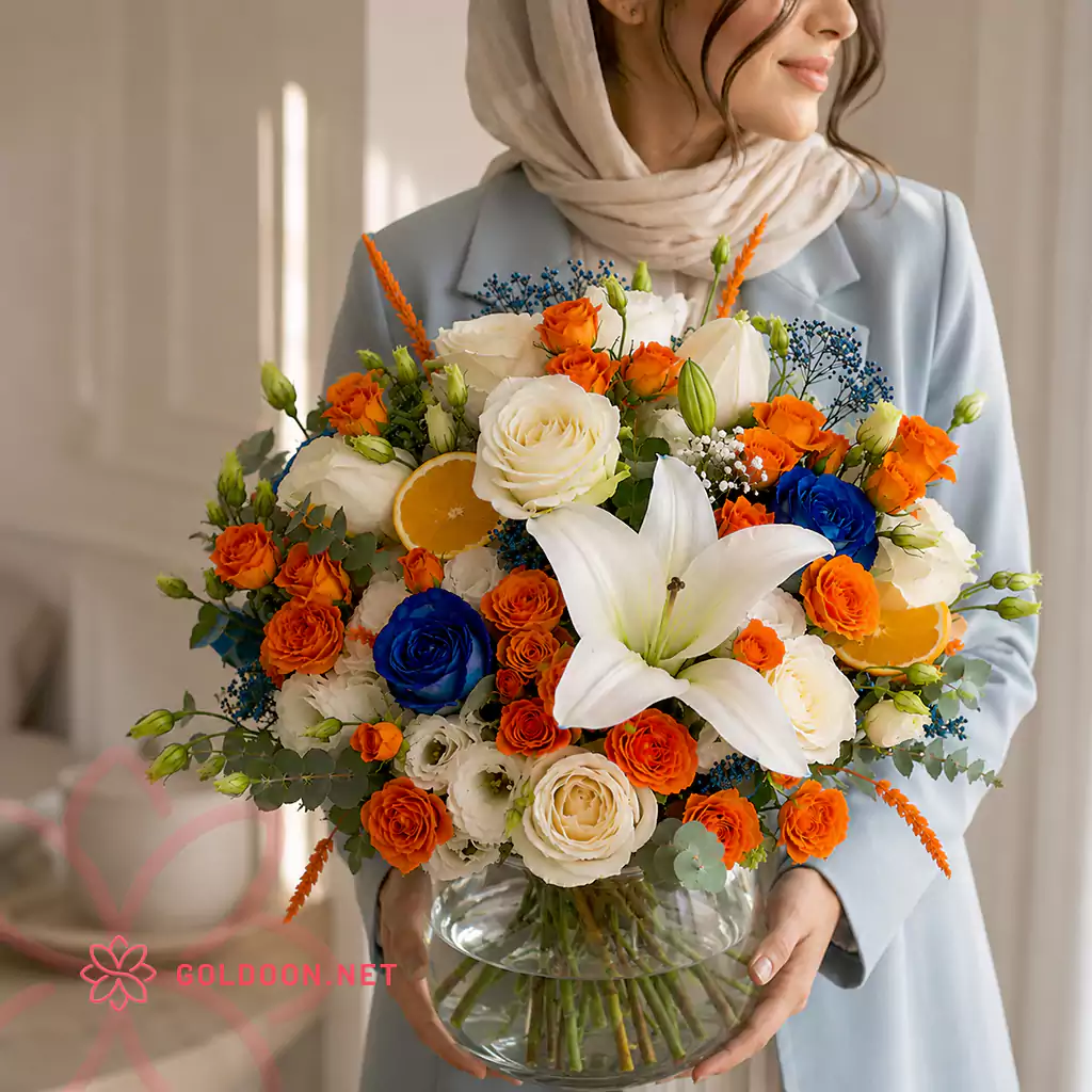 جار گل کد 004 رز مینیاتوری نارنجی و آبی با لیلیوم سفید در جار شیشهای از فروشگاه گلدون در دستان مدل خانم