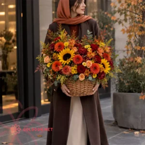 سبد گل کد 002 با ترکیب پاییزی آفتابگردان، ژربرا، رز و داوودی در سبد حصیری، در دست مدل خانم در خیابان