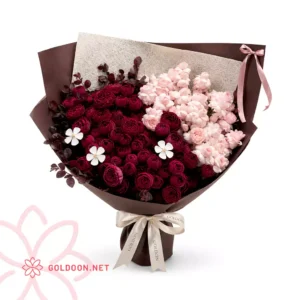 دسته گل رز ژولیت کد 014 از فروشگاه گلدون؛ ترکیبی پرحجم از گل رز ژولیت قرمز شرابی و گل‌های صورتی روشن در کنار برگ‌های تیره‌ی تزئینی، در بسته‌بندی کاغذ قهوه‌ای شکلاتی با روبان ساتن