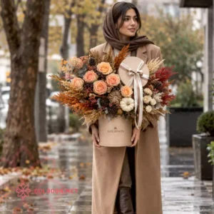 باکس گل و هدیهی پاییزی کد 040 با جعبهی هدیهی گرد و روبان لوگودار در دستان مدل خانم در تهران