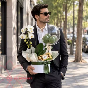 باکس گل ارکیده و بادکنک کد 037 یک هدیه مردانه با ارکیده سفید، شکلات فررو روشر اصل و بادکنک در باکس سفید در دست مدل آقا