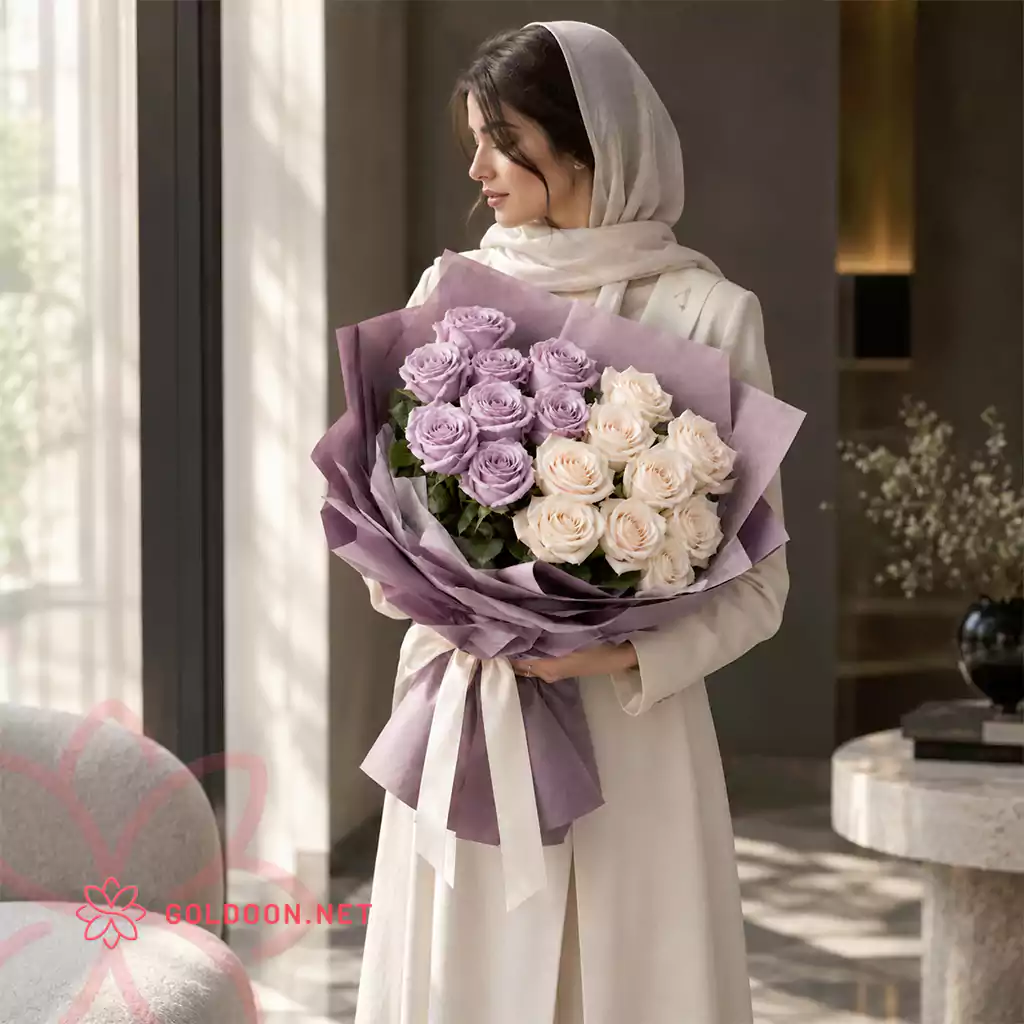 دسته گل رز دو رنگ کد 016 با رز یاسی و کرم و برگ سبز در بستهبندی یاسی با روبان ساتن در دستان مدل خانم